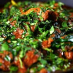 Close-up lamb saag or saagwala (lamb and spinach curry) with naan and coriander.