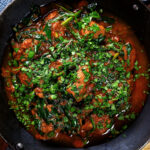 Overhead close-up lamb saag or saagwala (lamb and spinach curry) with naan and coriander.
