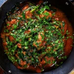 Overhead close-up lamb saag or saagwala (lamb and spinach curry) with naan and coriander.