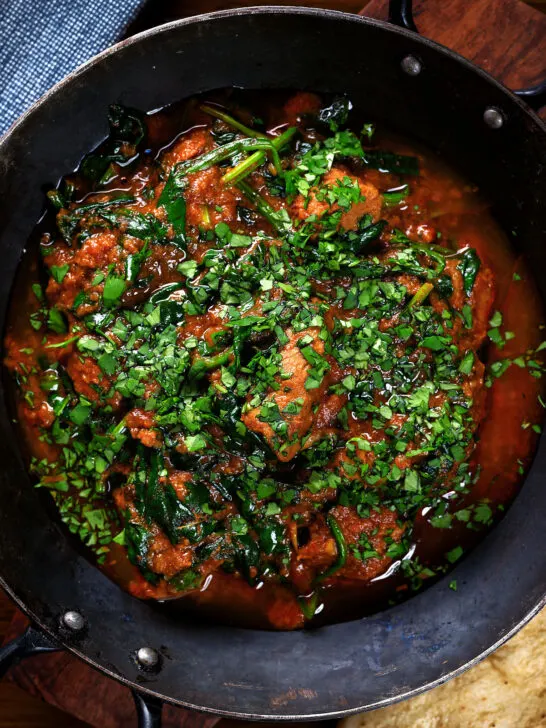 Overhead close-up lamb saag or saagwala (lamb and spinach curry) with naan and coriander.