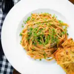 Overhead miso butter pasta with pecorino, black & pink peppercorns and chives served with garlic bread.