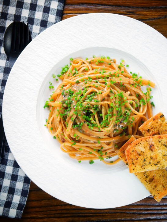 Overhead miso butter pasta with pecorino, black & pink peppercorns and chives served with garlic bread.