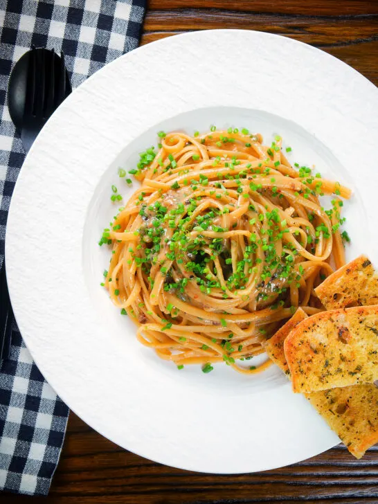 Overhead miso butter pasta with pecorino, black & pink peppercorns and chives served with garlic bread.