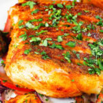Close-up pan fried curried cod fillet with cumin potatoes and tomato & onion salad.