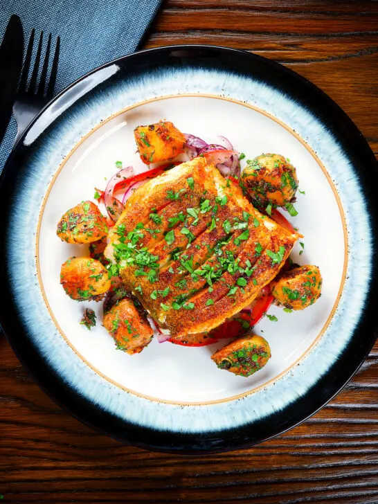 Overhead pan fried curried cod fillet with aloo jeera and tomato & onion salad.