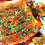 Close-up overhead pan fried curried cod fillet with cumin potatoes and tomato & onion salad.