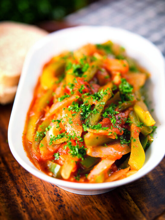 Basque piperade a pepper, onion and tomato stew garnished with parsley and served with bread.