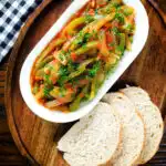 Overhead Basque piperade a pepper, onion and tomato stew garnished with parsley and served with bread.