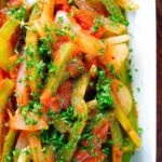 Close-up overhead Basque piperade a pepper, onion and tomato stew garnished with parsley.