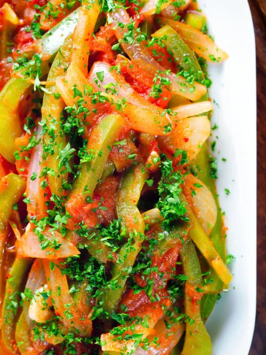 Close-up overhead Basque piperade a pepper, onion and tomato stew garnished with parsley.