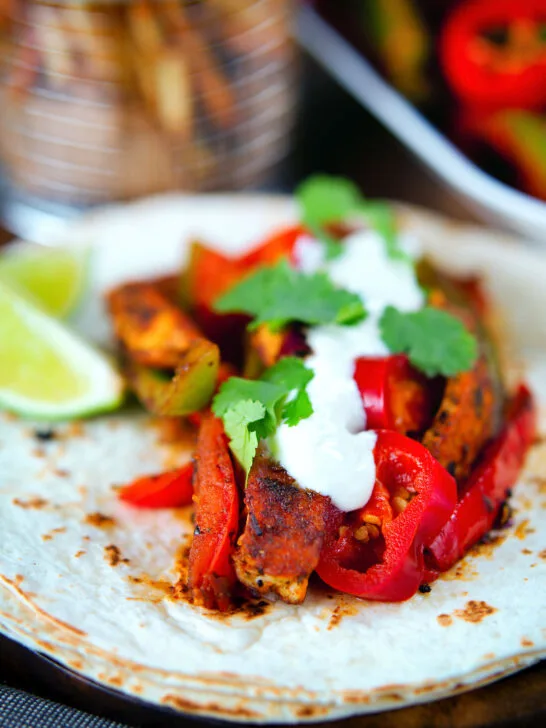 Spicy Mexican influenced halloumi cheese and vegetable fajitas with lime wedges.
