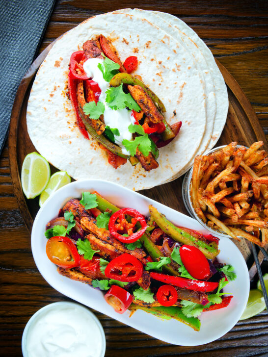 Overhead spicy Mexican influenced halloumi cheese and vegetable fajitas with lime wedges.