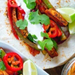 Overhead Close up Mexican influenced halloumi cheese and vegetable fajitas with lime wedges.