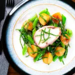 Overhead bacon wrapped monkfish with potatoes, samphire and sugar snap peas in butter and cider.