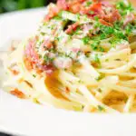 Close-up chicken and crispy bacon pasta (linguine) in a creamy white wine and garlic sauce.