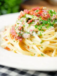 Close-up chicken and crispy bacon pasta (linguine) in a creamy white wine and garlic sauce.