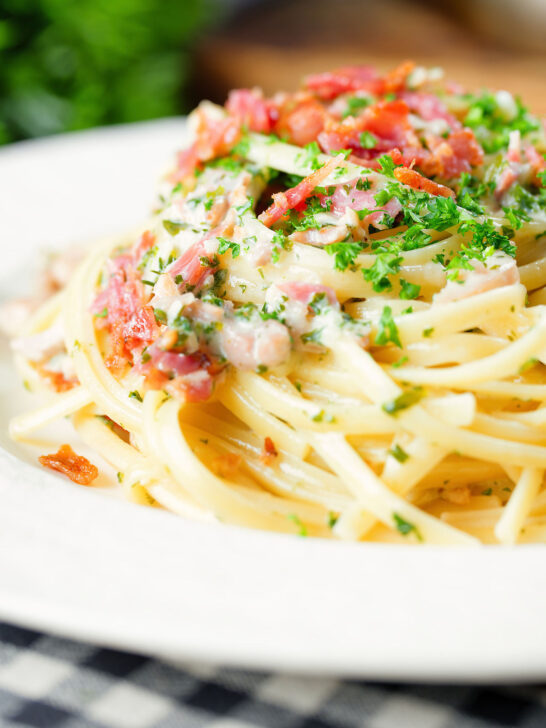 Close-up chicken and crispy bacon pasta (linguine) in a creamy white wine and garlic sauce.