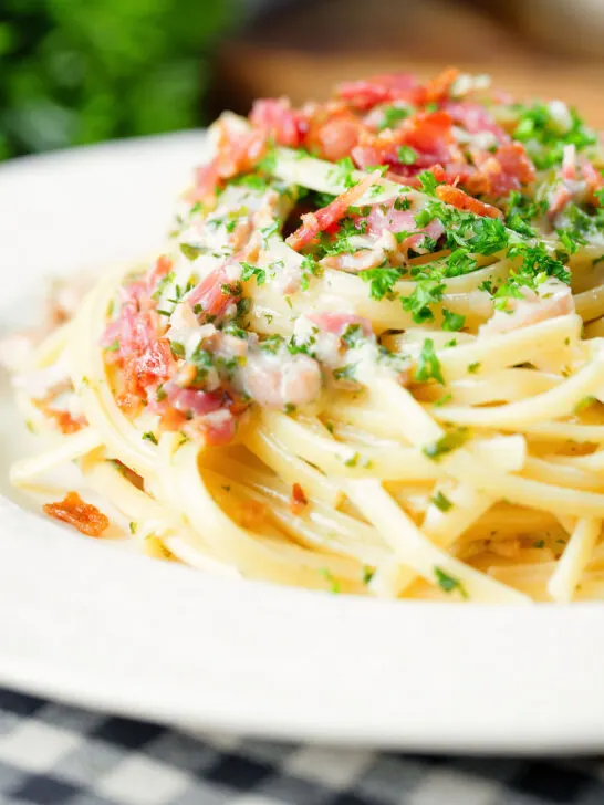 Close-up chicken and crispy bacon pasta (linguine) in a creamy white wine and garlic sauce.