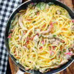 Overhead chicken and crispy bacon pasta (linguine) in a creamy white wine and garlic sauce.