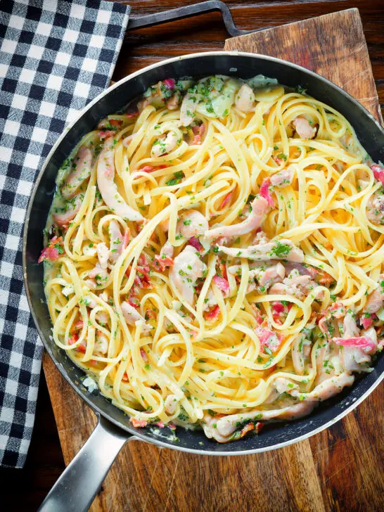 Overhead chicken and crispy bacon pasta (linguine) in a creamy white wine and garlic sauce.