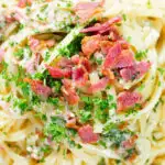 Close-up overhead chicken and crispy bacon pasta (linguine) in a creamy white wine and garlic sauce.