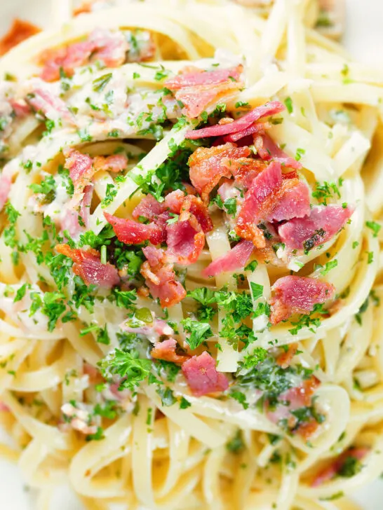 Close-up overhead chicken and crispy bacon pasta (linguine) in a creamy white wine and garlic sauce.