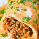 Close-up Hortobágyi palacsinta Hungarian meat stuffed pancakes in a sour cream and paprika sauce.