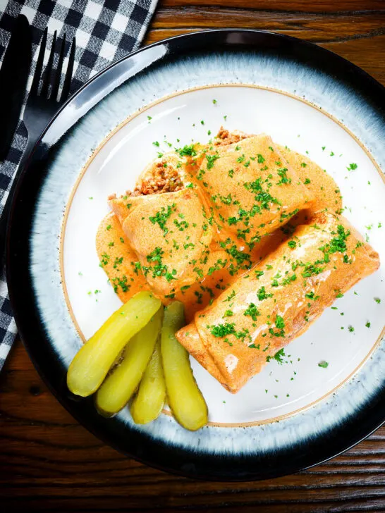 Overhead Hortobágyi palacsinta Hungarian meat stuffed pancakes in a sour cream and paprika sauce.