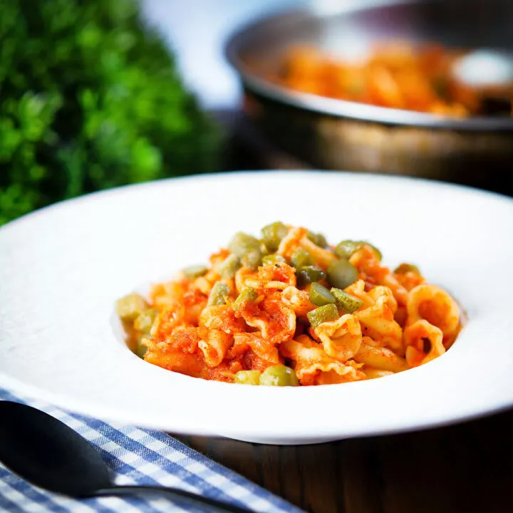 Hungarian potato and paprika pasta (Krumplis Teszta) with pickles in a white bowl.