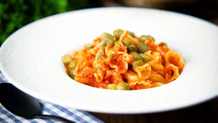 Hungarian potato and paprika pasta (Krumplis Teszta) with pickles in a white bowl.