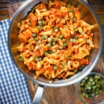 Overhead Hungarian potato and paprika pasta (Krumplis Teszta) with pickles in a cooking pan.