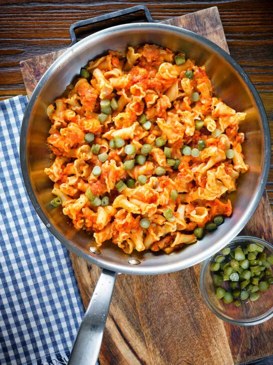 Overhead Hungarian potato and paprika pasta (Krumplis Teszta) with pickles in a cooking pan.