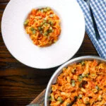 Overhead Hungarian potato and paprika pasta (Krumplis Teszta) served with pickles.