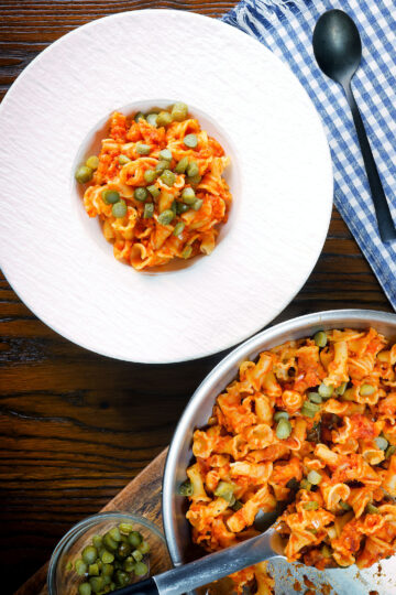 Overhead Hungarian potato and paprika pasta (Krumplis Teszta) served with pickles.