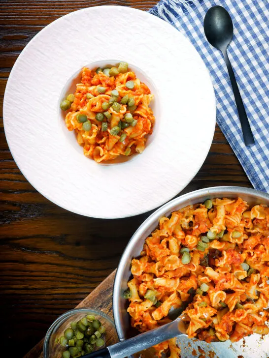Overhead Hungarian potato and paprika pasta (Krumplis Teszta) served with pickles.