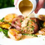 Close-up pork tenderloin medallions with a cider, mustard and camembert sauce, new potatoes and asparagus.