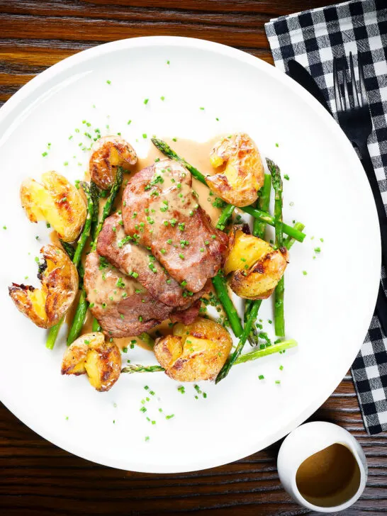 Overhead pork tenderloin medallions with a cider, mustard and camembert sauce, new potatoes and asparagus.