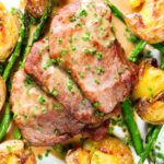 Overhead close-up pork tenderloin medallions with a cider, mustard and camembert sauce, new potatoes and asparagus.