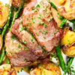 Overhead close-up pork tenderloin medallions with a cider, mustard and camembert sauce, new potatoes and asparagus.