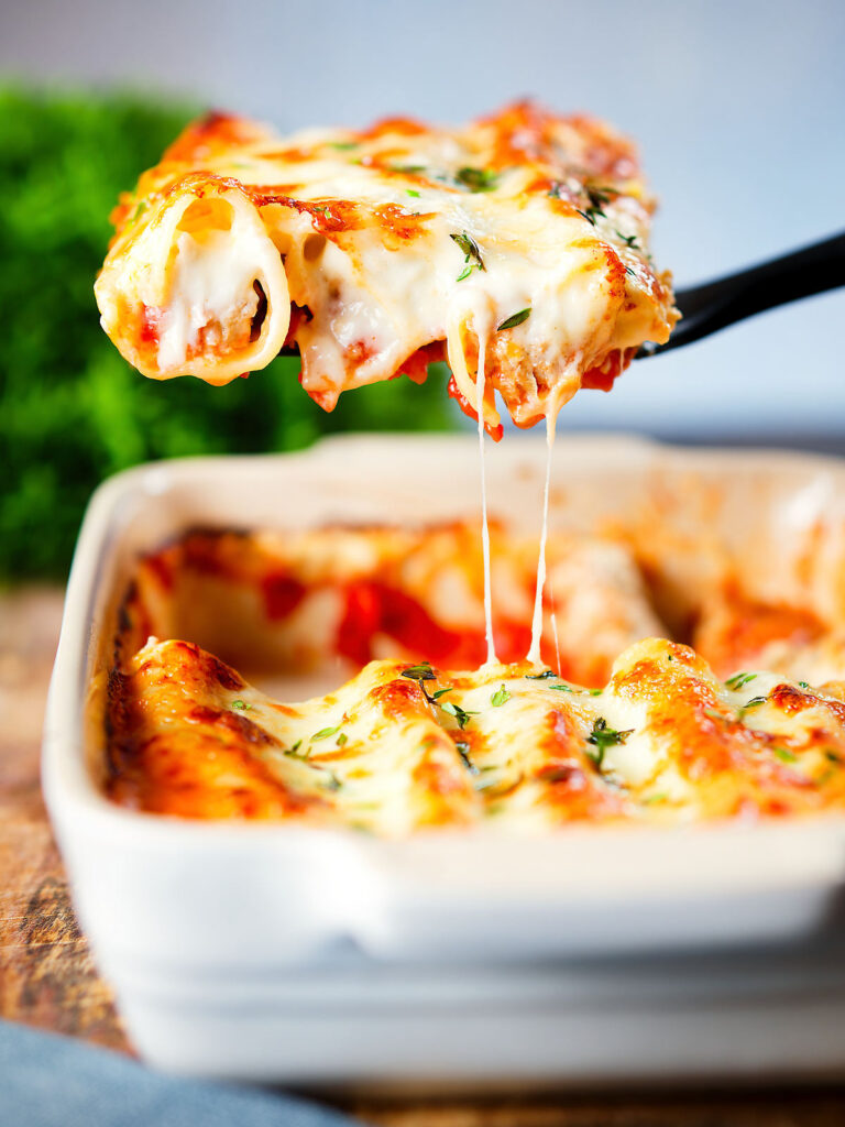 Baked three cheese pork sausage, leek and ricotta stuffed cannelloni being served.