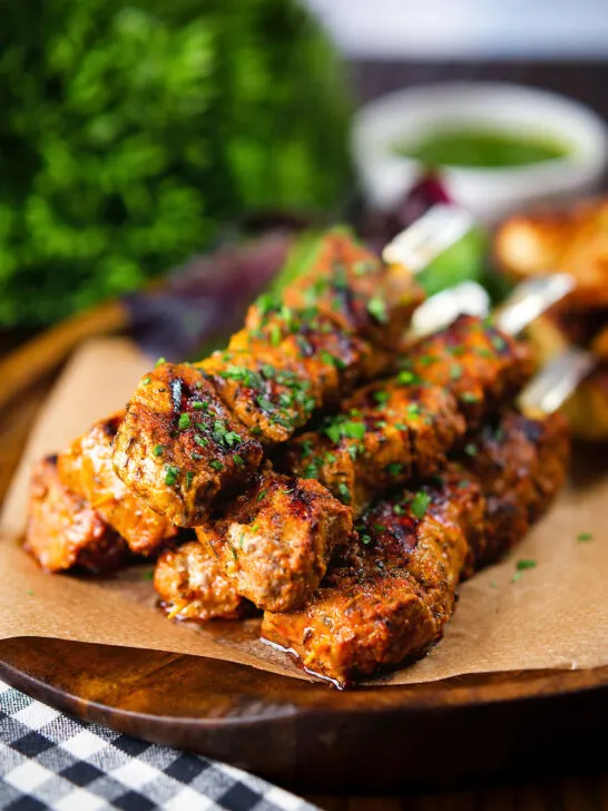 Spanish Pinchos morunos (pork skewers) served with a parsley salsa and potato wedges.