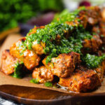 Close-up Spanish Pinchos morunos (pork skewers) served with a garlic & parsley salsa.