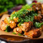 Close-up Spanish Pinchos morunos (pork skewers) served with a garlic & parsley salsa.