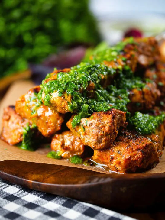 Close-up Spanish Pinchos morunos (pork skewers) served with a garlic & parsley salsa.