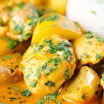 Close-up Thai yellow chicken curry with new potatoes, shallots, steamed jasmine rice and coriander.