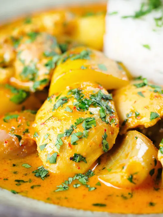 Close-up Thai yellow chicken curry with new potatoes, shallots, steamed jasmine rice and coriander.