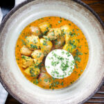 Overhead Thai yellow chicken curry with new potatoes, shallots, steamed jasmine rice and coriander.