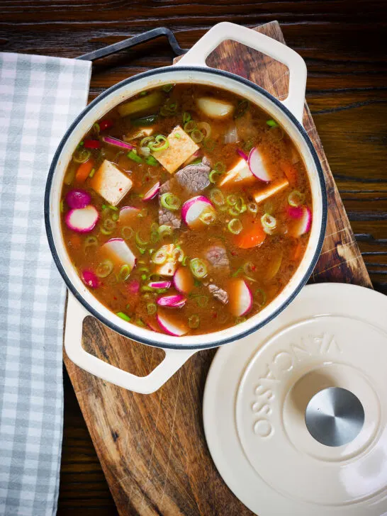 Overhead close-up Korean beef doenjang jjigae stew with vegetables and tofu in it's cooking pot.