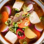 Overhead close-up Korean beef doenjang jjigae stew with vegetables and tofu.