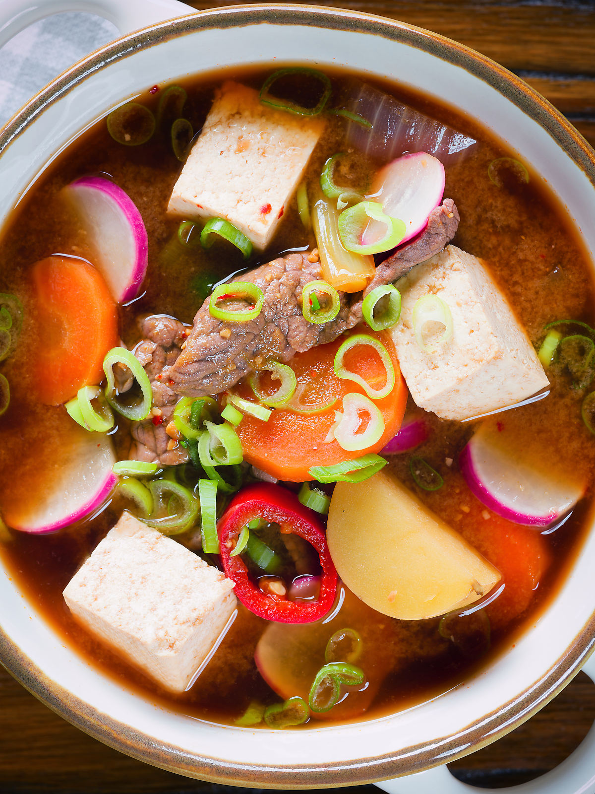 Overhead close-up Korean beef doenjang jjigae stew with vegetables and tofu.